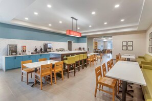 A modern dining area with multiple tables and chairs, a kitchen counter, and a bar area.