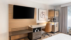 A hotel room with a bed, a desk with a chair, a television, a framed artwork, a cabinet, and a window with curtains. - Country Inn & Suites by Radisson, Savannah Airport, GA (Savannah)