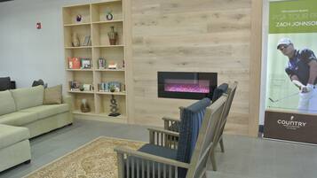 Una sala moderna con sofá, sillas, chimenea y estantería.