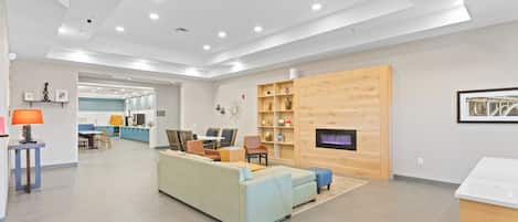 A spacious living area with a sofa, chairs, a fireplace, and a kitchen in the background.