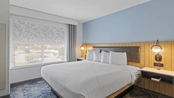 Habitación de hotel con una cama grande, dos mesitas de noche con lámparas, un ventanal con vistas y una alfombra estampada.
