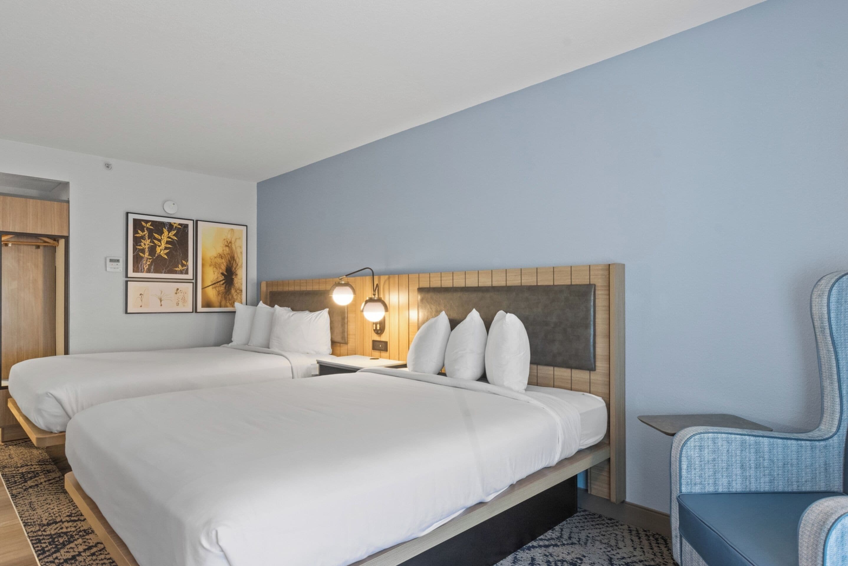 A hotel room with two beds, a seating area, and artwork on the walls.