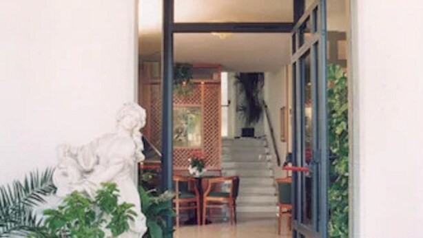 Eine Steintreppe führt zu einem Raum mit Blick auf einen Garten und eine Statue.