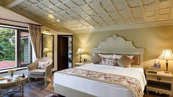 Habitación de hotel con una cama grande, un área de descanso con una silla, una mesita y vistas al exterior.