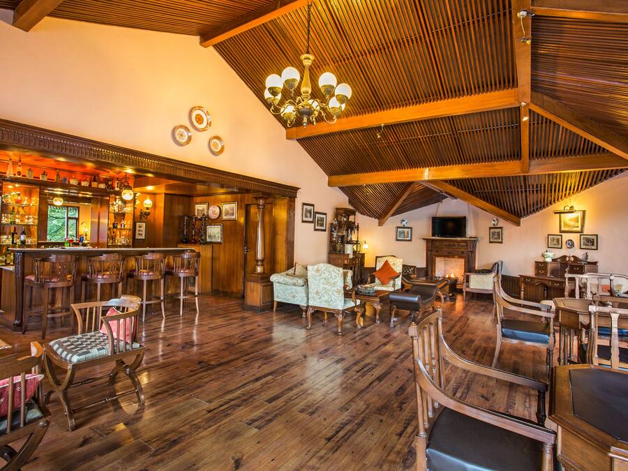 A spacious room with wooden floors, a bar area, and multiple seating arrangements including chairs and sofas.