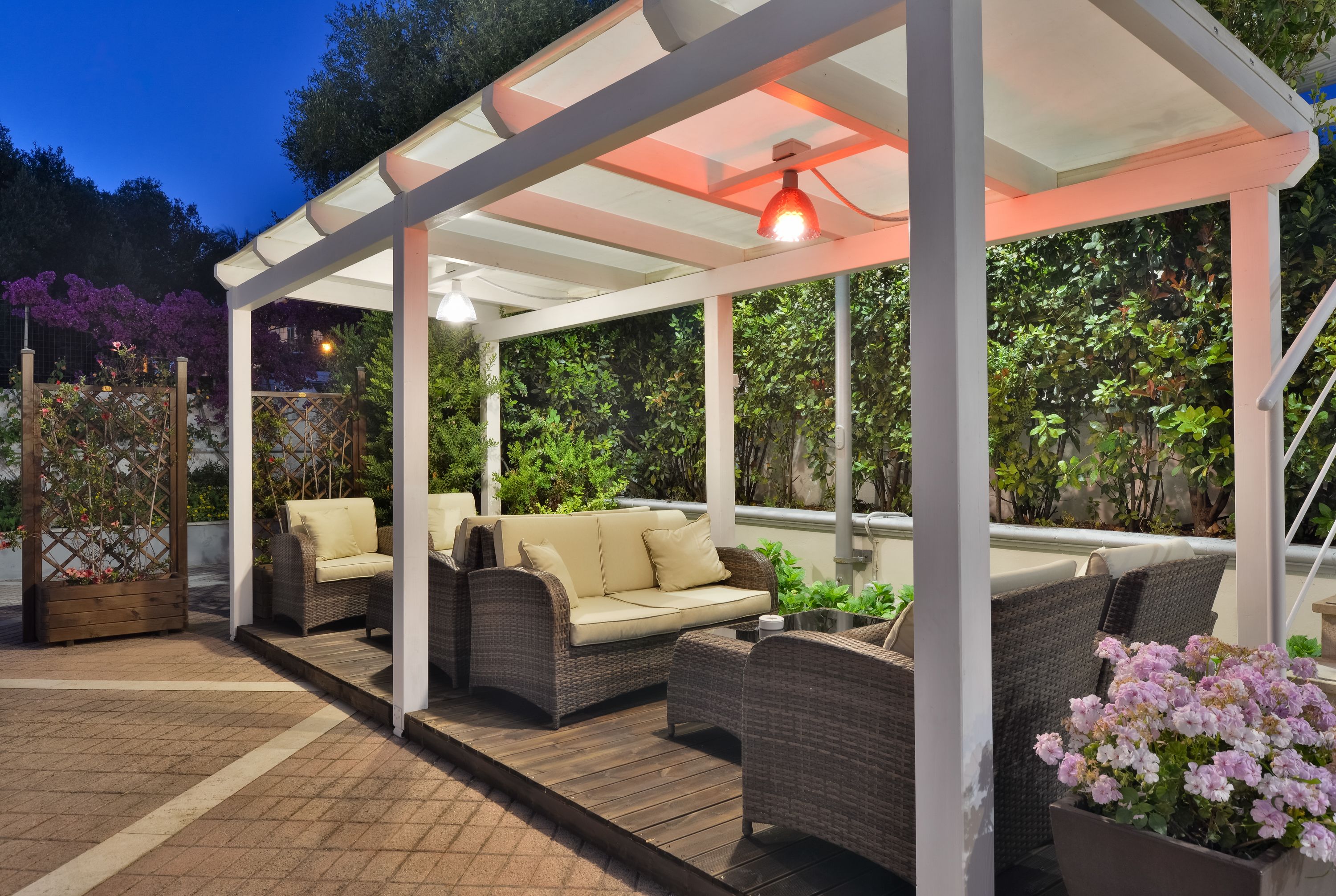 A covered outdoor seating area with wicker furniture and a potted plant.