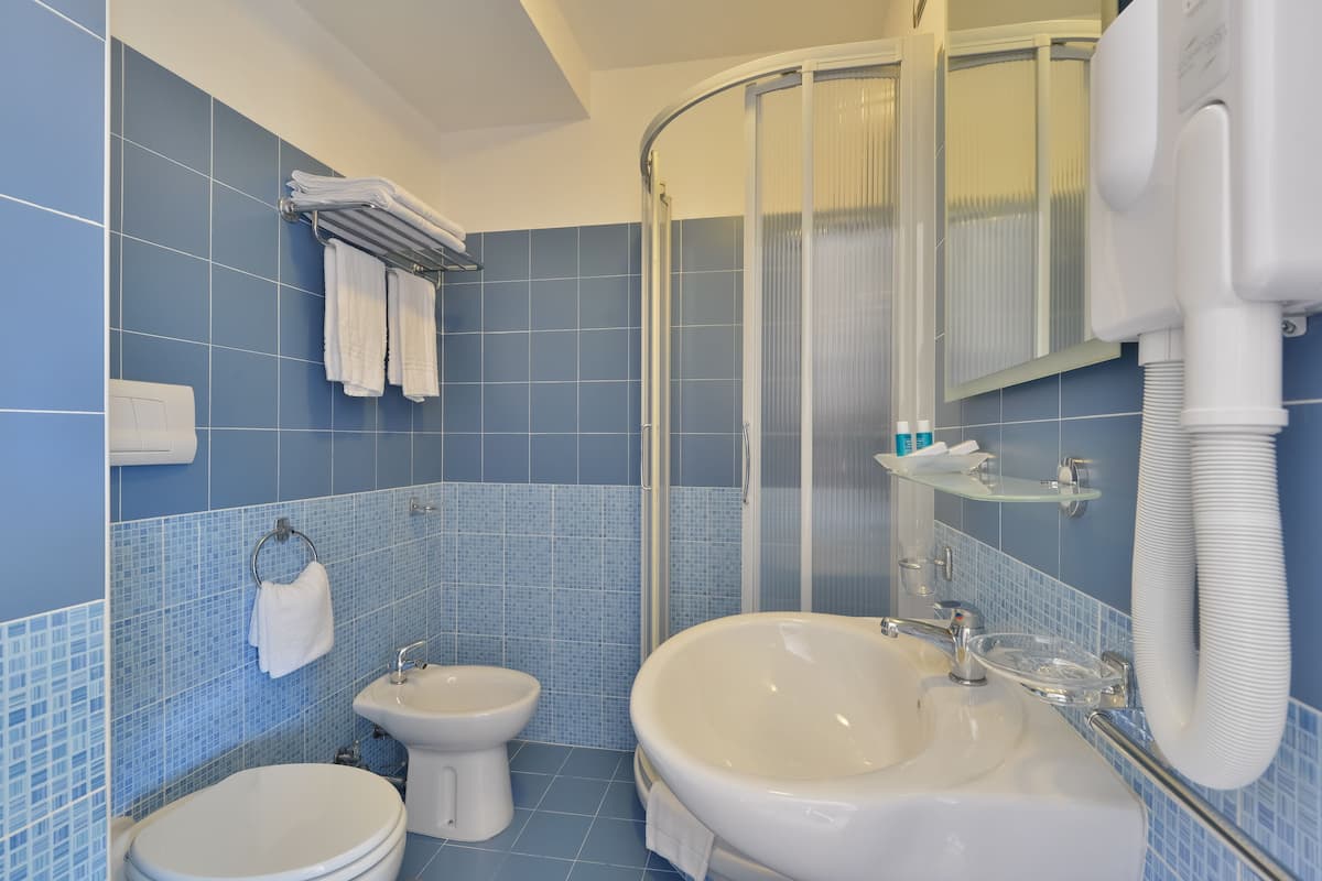A bathroom with a shower, a sink, and two toilets.