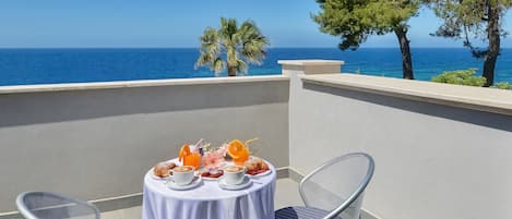 En balkong med ett bord dukat för frukost, med utsikt över havet.