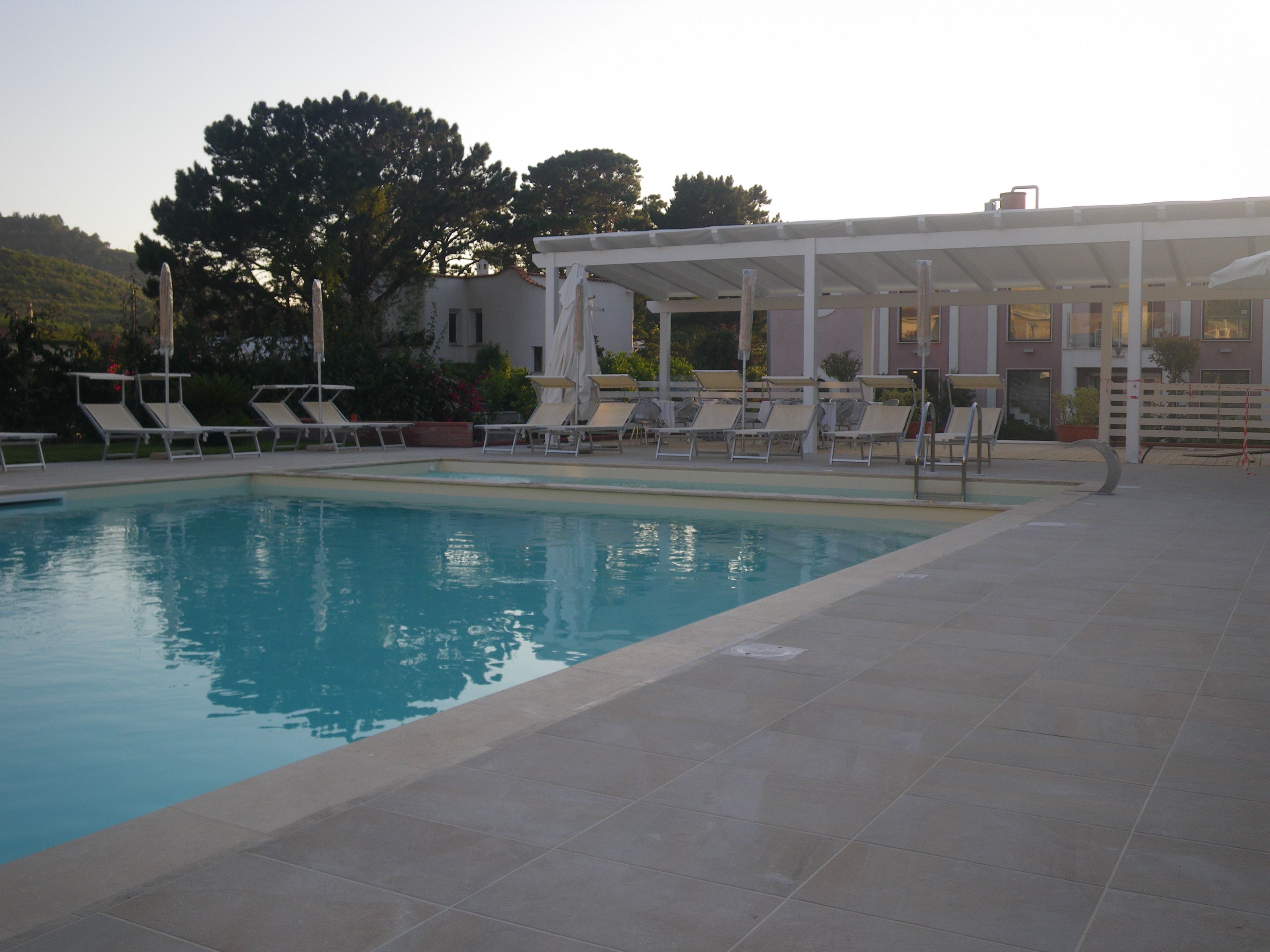 Una piscina con lettini e una zona relax coperta.