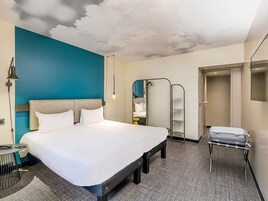 Una habitación de hotel con cama, escritorio, silla, armario y espejo.