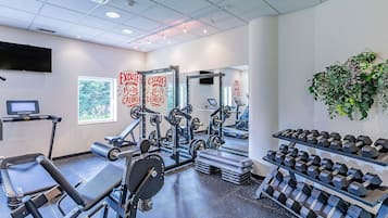 A gym with exercise equipment, treadmills, and dumbbells.