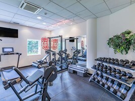 Un gimnasio con equipo de ejercicio, cintas de correr y mancuernas.