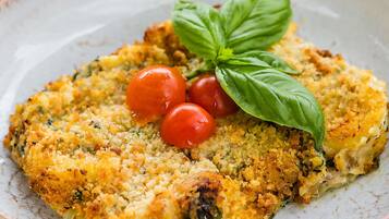 Um prato com crosta dourada, tomates cereja e uma folha de manjericão.