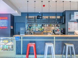 A bar area with a counter, stools, and a variety of bottles and glasses. - ibis Lisboa Alfragide (Amadora)