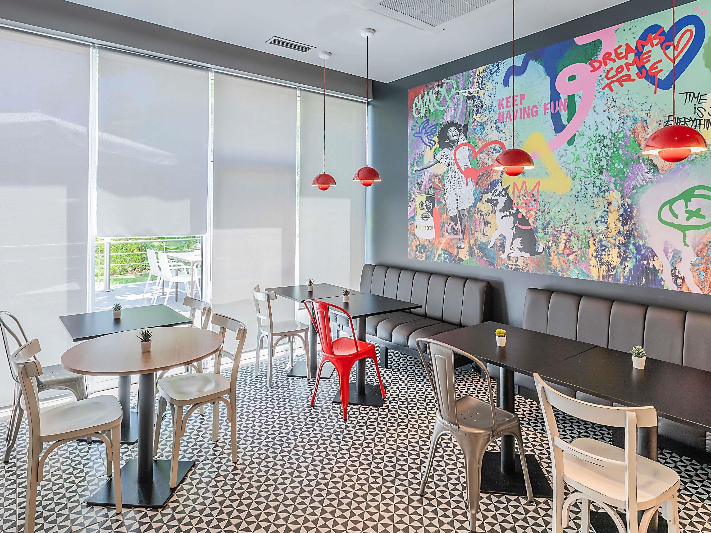 Un interior moderno con un gran mural abstracto, una variedad de opciones de asiento y un suelo con estampado geométrico.
