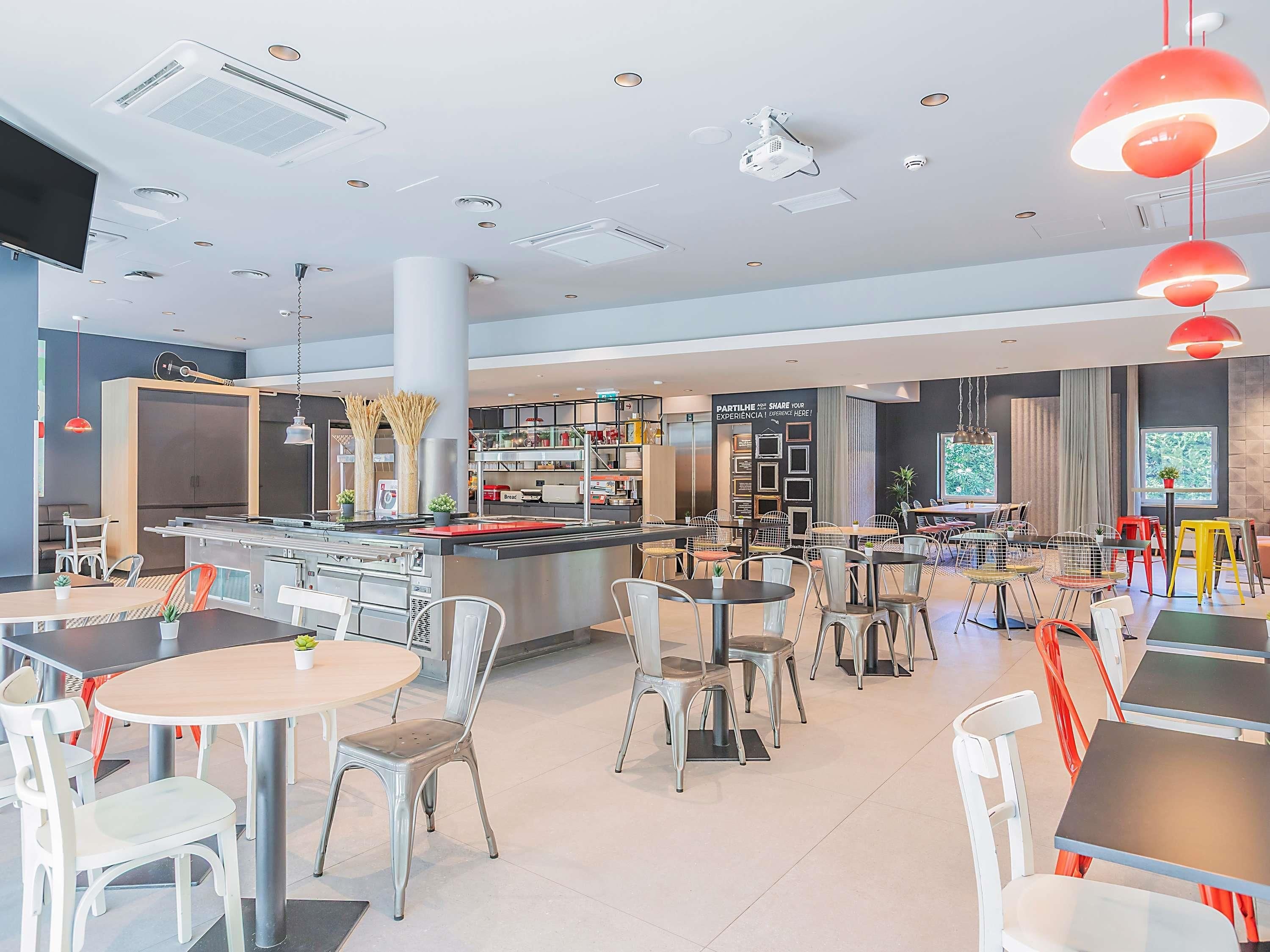 Un restaurante moderno con barra central, varias zonas de estar y cocina a la vista.