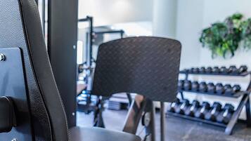 Ein Fitnessstudio-Innenraum mit Trainingsgeräten, einem Stuhl und einem Dumbbell-Gestell.