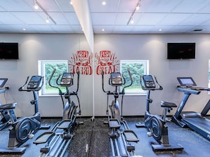 A gym with mirrored walls, exercise equipment, motivational posters, and a large window. - ibis Lisboa Alfragide (Amadora)