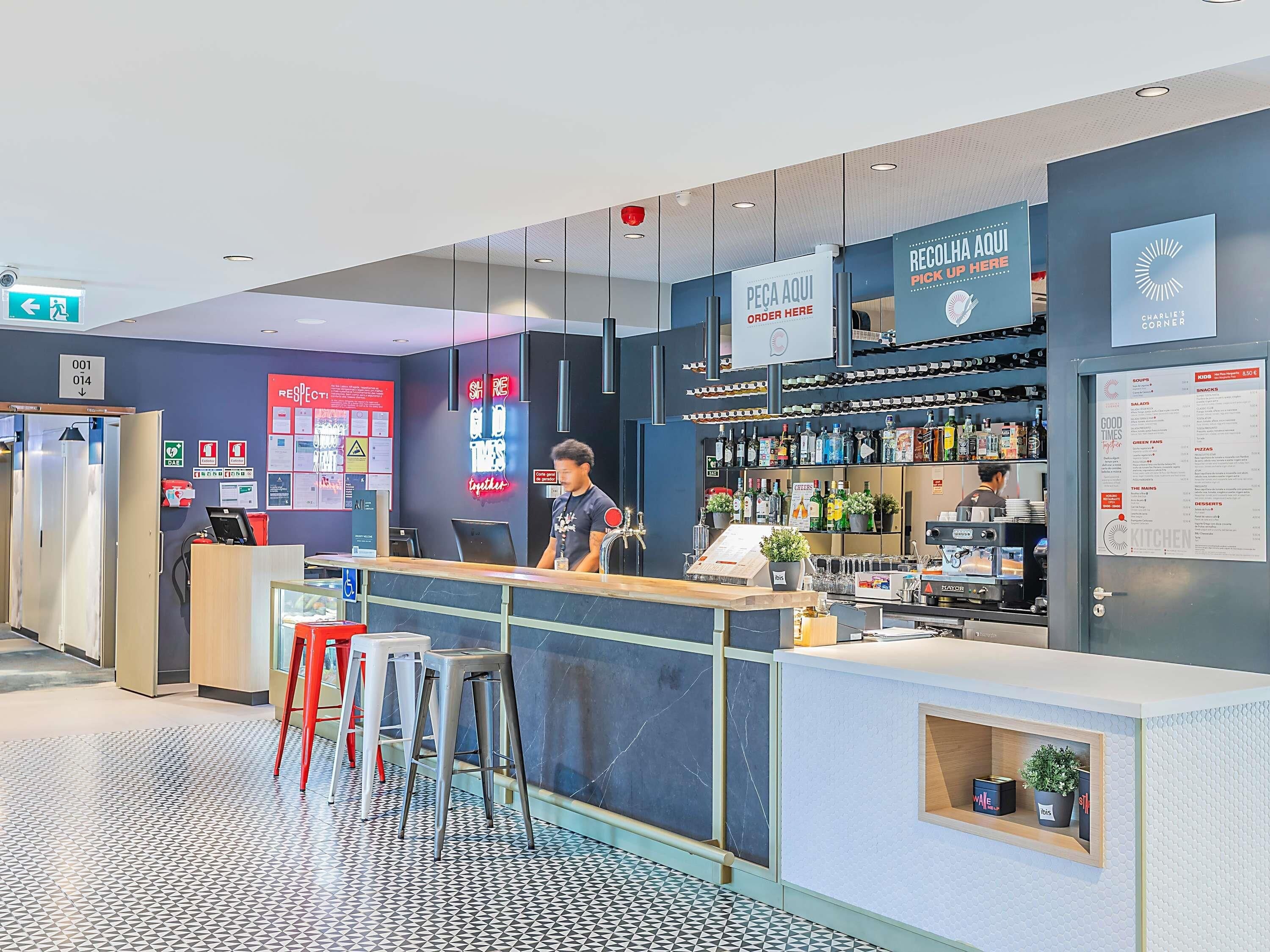 A modern bar area with a counter, stools, and a menu board.