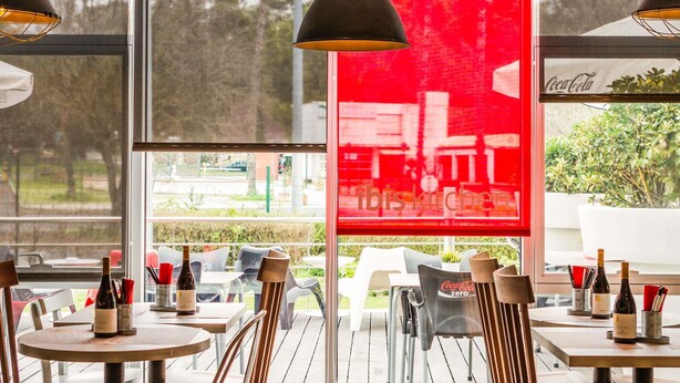An outdoor dining area with tables, chairs, and bottles of wine. - ibis Lisboa Alfragide (Amadora)