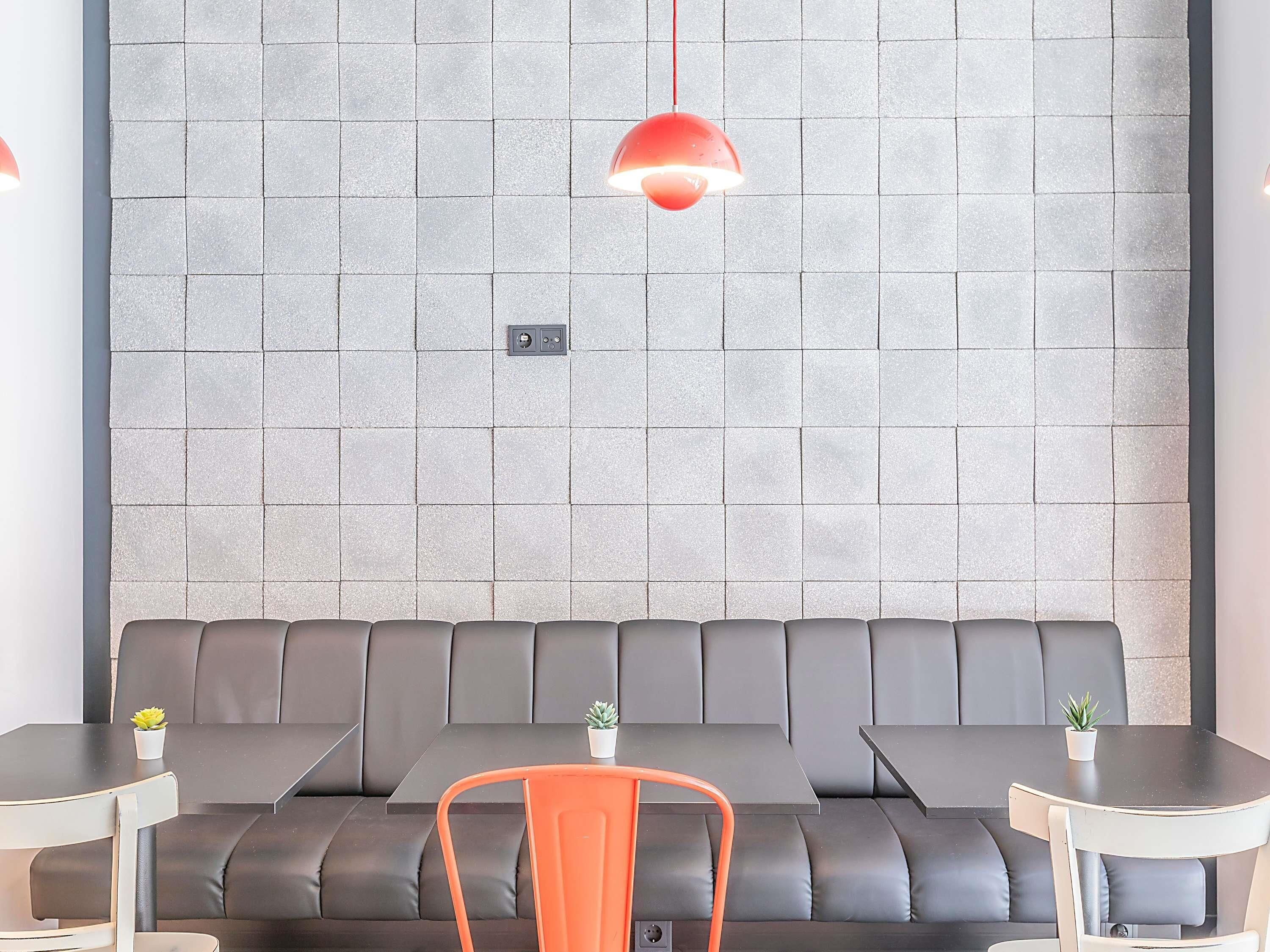 A modern seating area with a black sofa and two small tables, each with a potted plant.