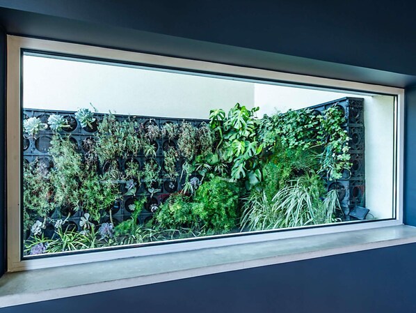 A window with a view of a vertical garden with various plants. - ibis Lisboa Alfragide (Amadora)