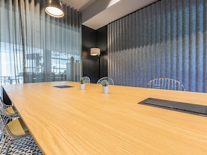A conference room with a wooden table, potted plants, and a black ruler. - ibis Lisboa Alfragide (Amadora)