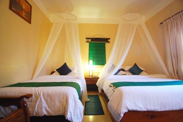 A hotel room with two beds, a nightstand, a green mat, and a hanging green curtain. - Shining Angkor Boutique Hotel (Siem Reap)