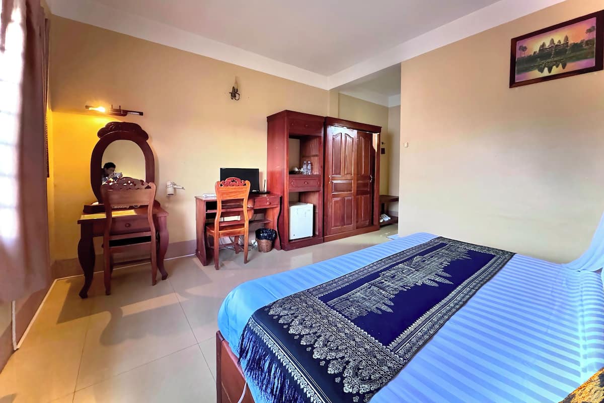 A bedroom with a bed, a desk, a chair, a wardrobe, and a mirror.