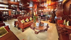 A traditional wooden interior with a sofa, decorative statues, and a chandelier. - Shining Angkor Boutique Hotel (Siem Reap)