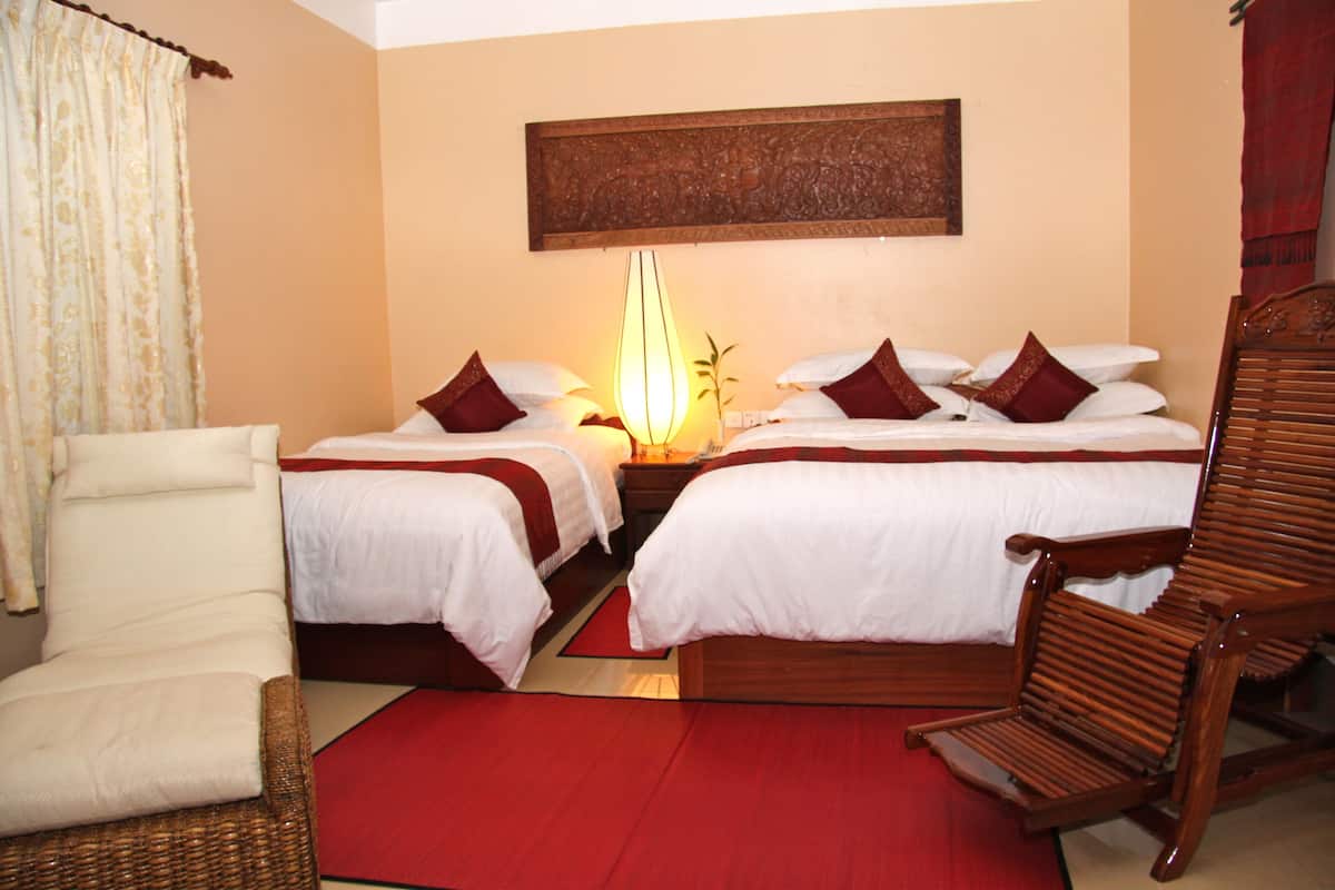 A hotel room with two beds, a wooden chair, a red rug, and a wall-mounted artwork.