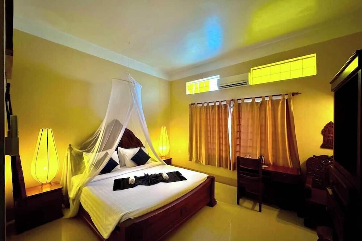 A hotel room with a bed, bedside lamps, a desk, and a chair.