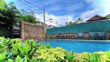Una piscina rodeada de exuberante vegetación y una valla de madera.