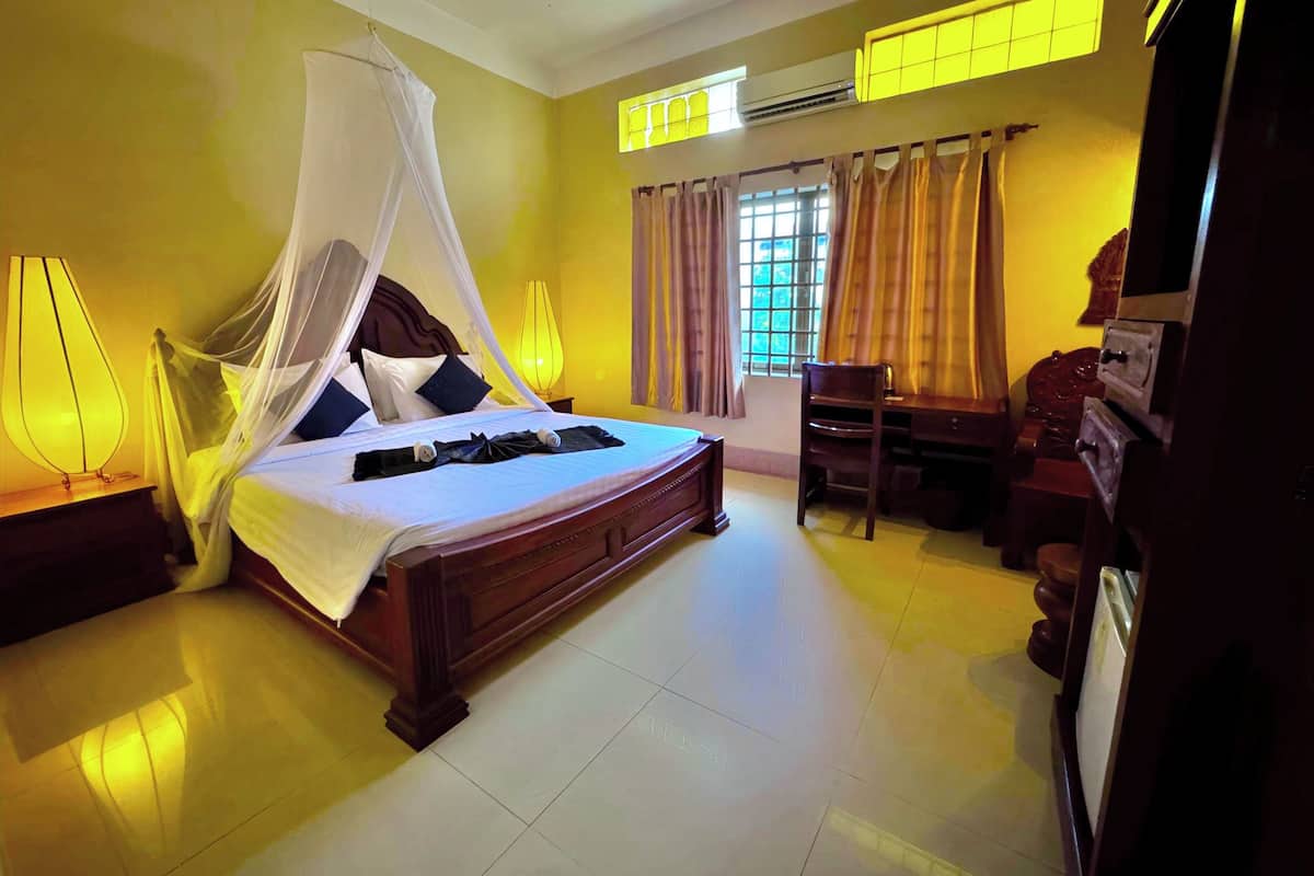 A bedroom with a four-poster bed, a desk, and a chair.