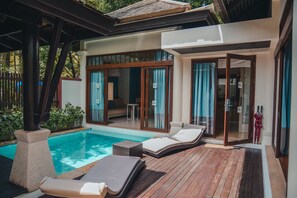 A poolside area with lounge chairs, a wooden deck, and a glass door leading to a room. - Melati Beach Resort & Spa (Koh Samui)
