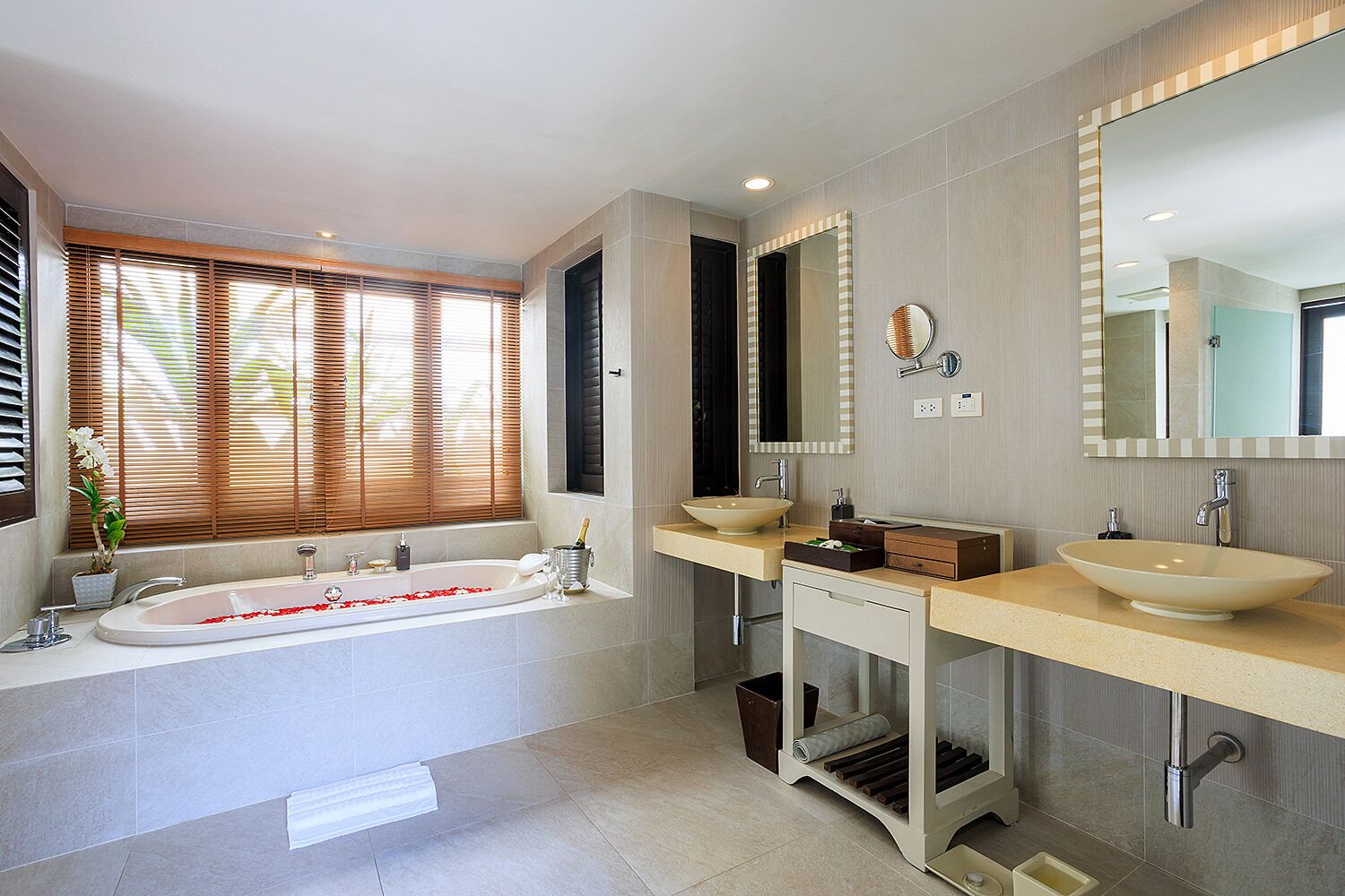A modern bathroom with a freestanding bathtub, two sinks, and a large mirror.