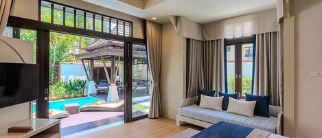 A modern hotel room with a large bed, a television, a desk, and a view of a swimming pool.