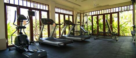 Un gimnasio con cintas de correr, elípticas y una bicicleta estática.