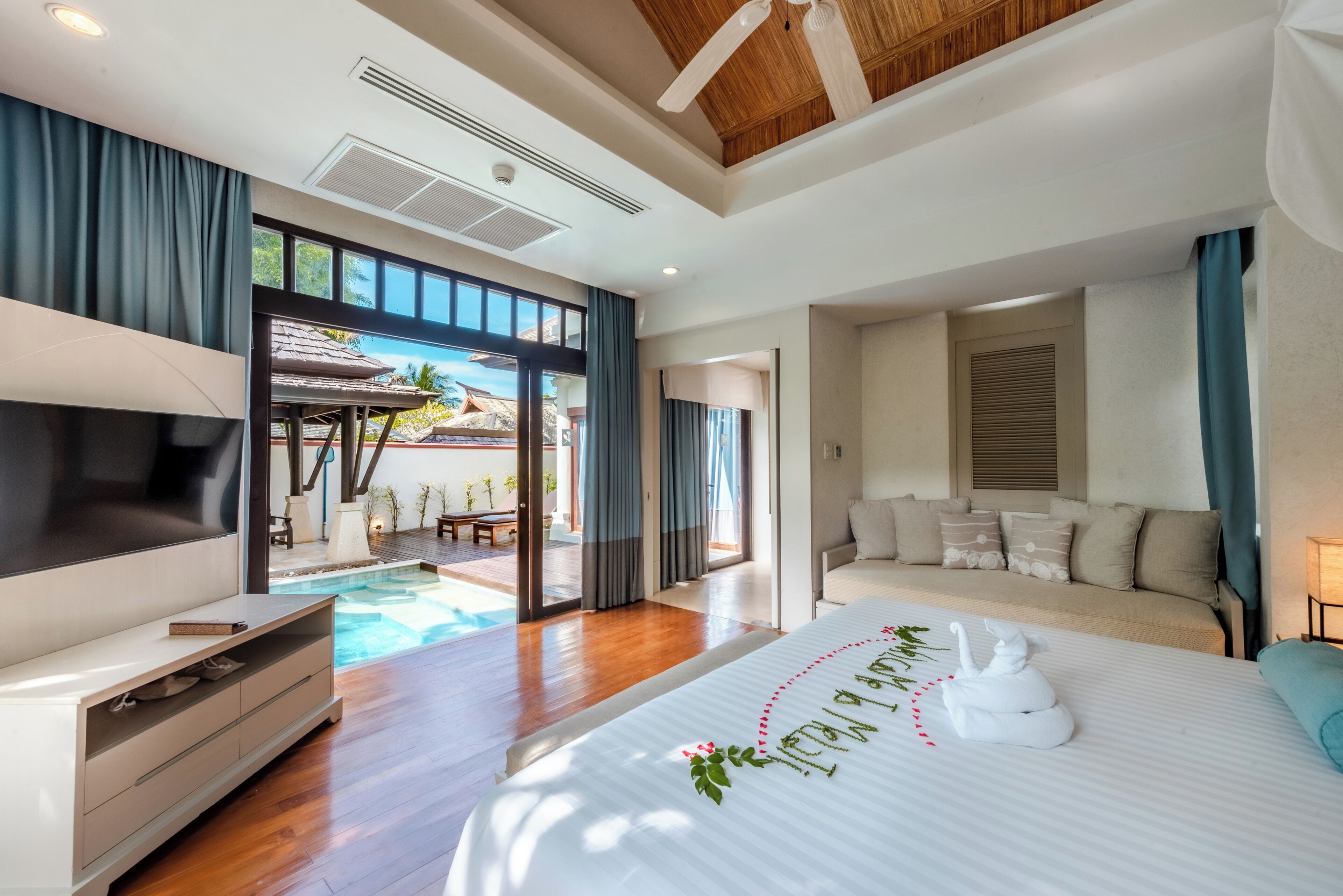 Habitación de hotel moderna con una cama grande, televisor y vistas a un área de piscina exterior.