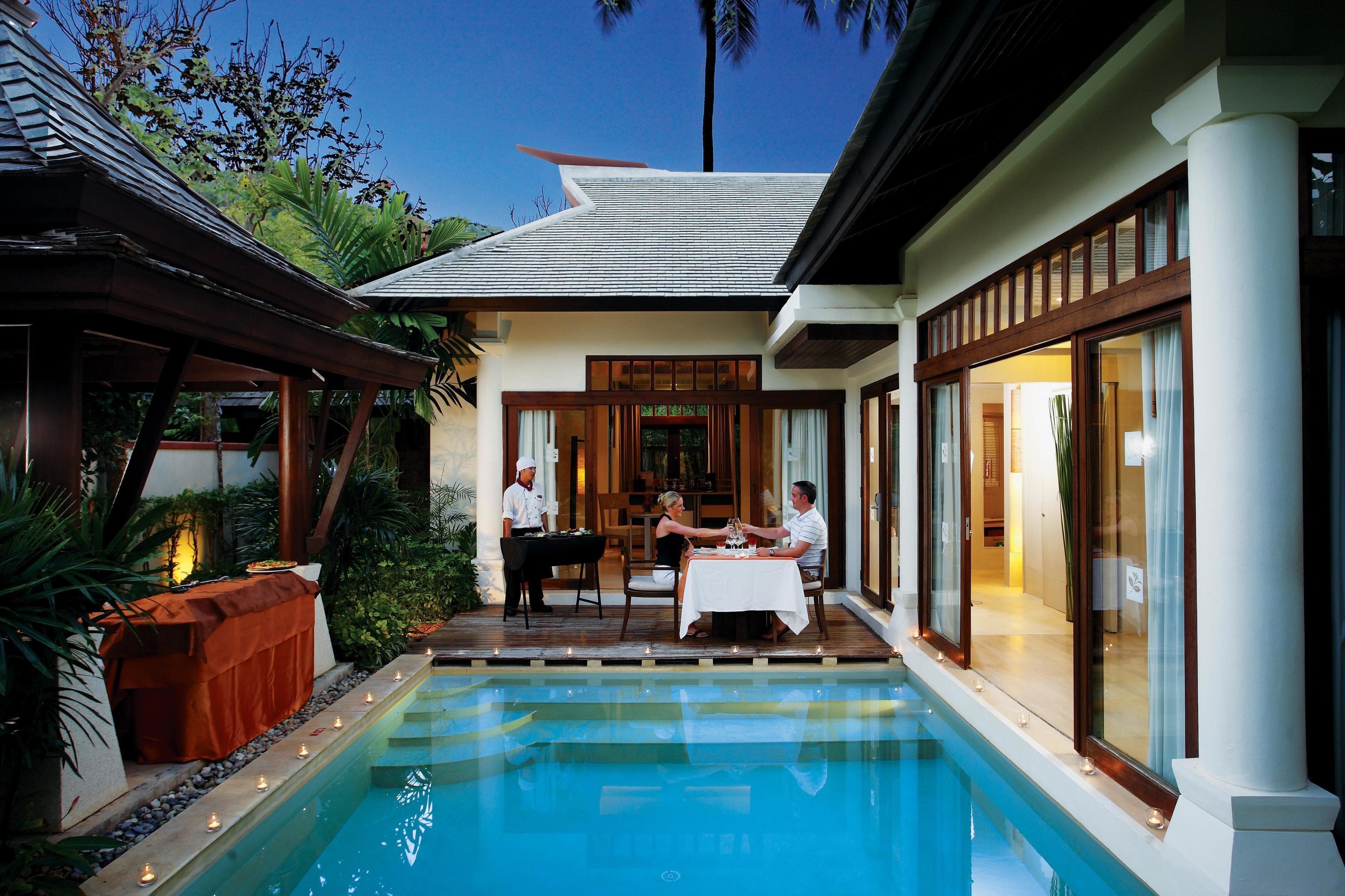 A dining area with a pool, a waiter, and a guest.