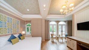 Una habitación de hotel con una cama grande, una zona de comedor y un televisor.