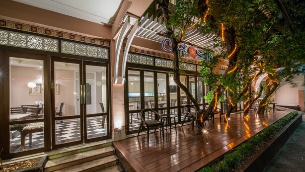 Un restaurante con suelo a cuadros, mesas al aire libre y un árbol decorado con luces.