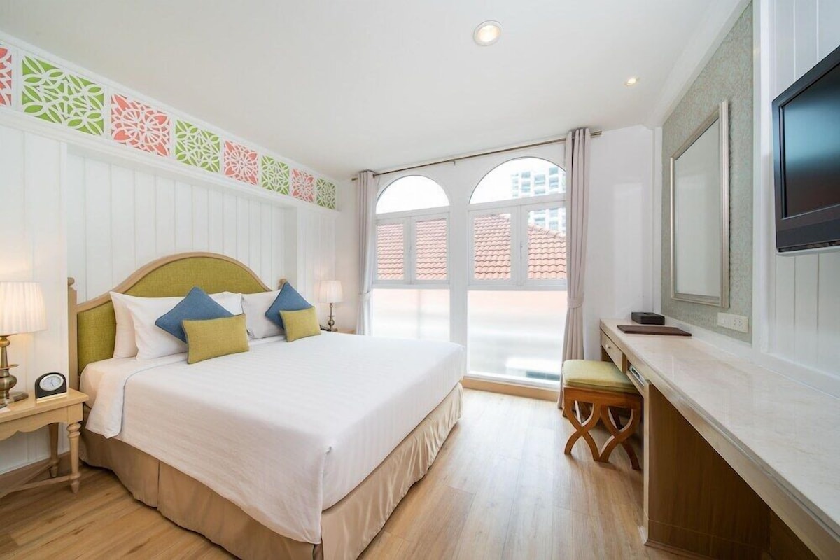 Habitación de hotel con cama, mesita de noche, lámpara y televisor.