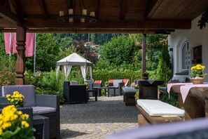 An outdoor patio with wicker furniture, a white canopy, and a stone floor.