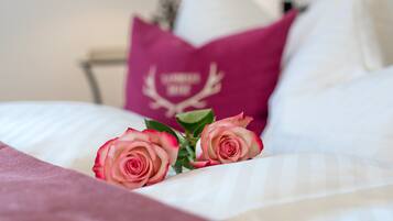 Een bed met roze rozen en een kussen met een hertenlogo.