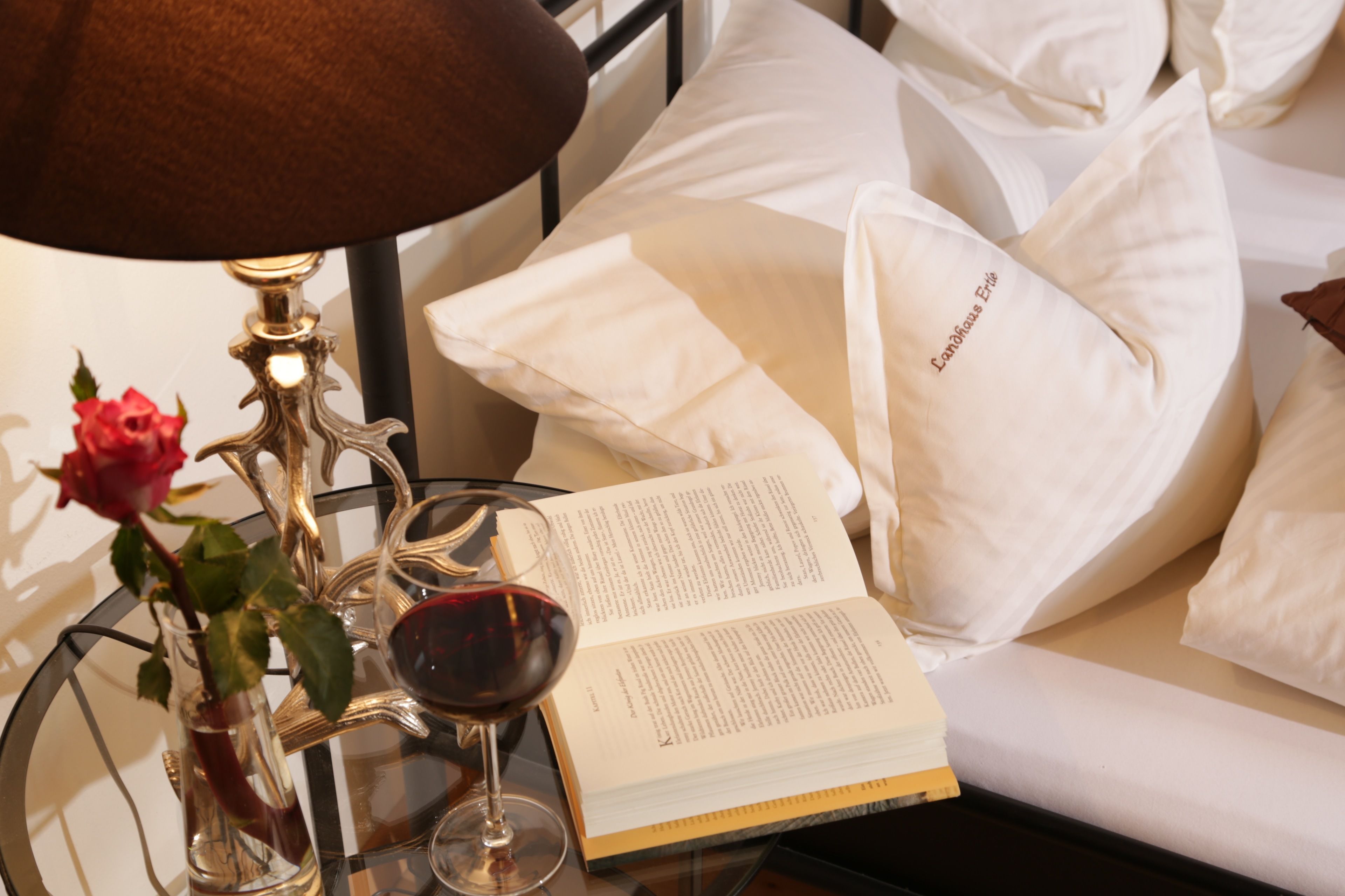 Una cama con almohadas blancas y un libro encima.