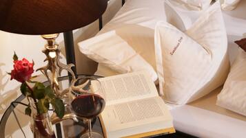 Una cama con almohadas blancas y un libro encima.