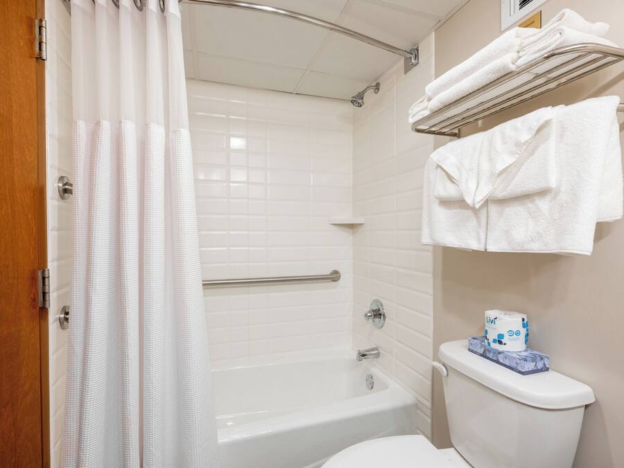 A bathroom with a bathtub, toilet, and a towel rack with towels.
