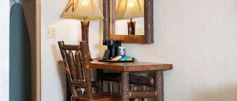 Un escritorio de madera con una silla, una lámpara y una cafetera.