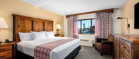 Une chambre d’hôtel avec un grand lit, un bureau, une commode et une fenêtre donnant sur un paysage urbain.